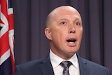 Home Affairs Minister Peter Dutton holds a Labor party document while talking to the media