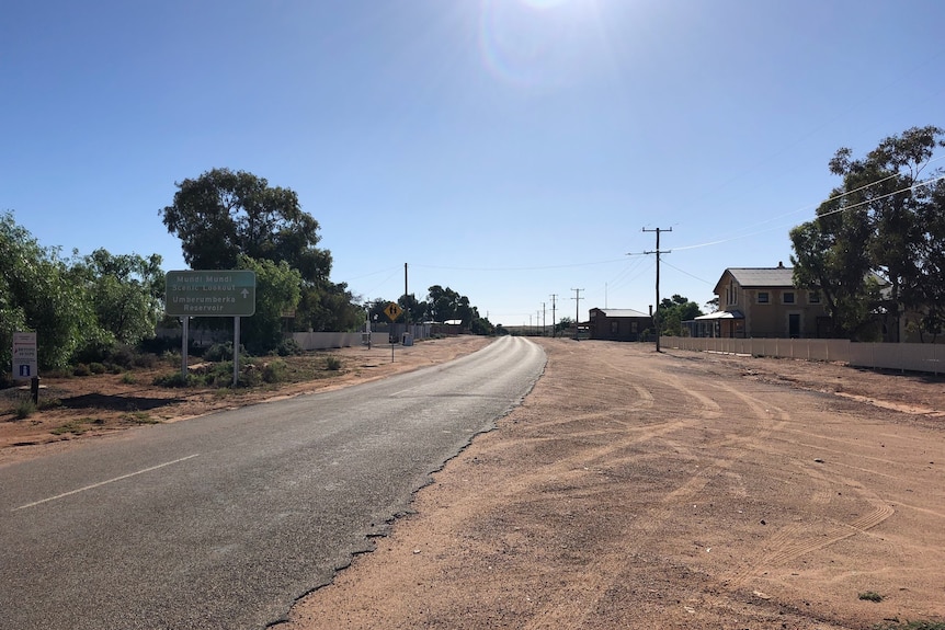 A dusty road on the outskirts of an outback town.