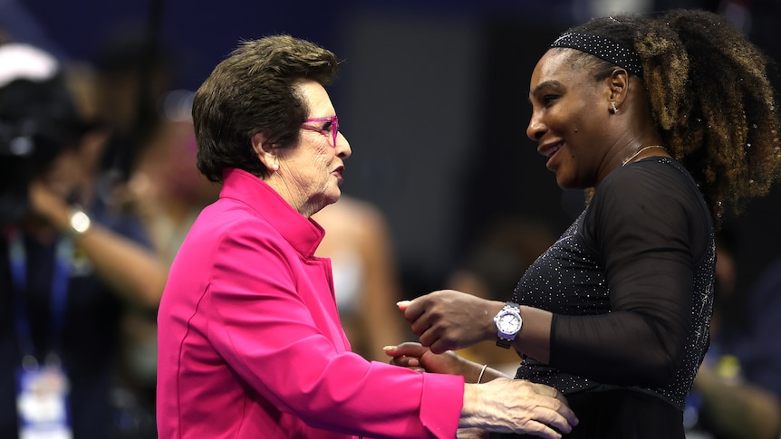 A pink-clad Billie Jean King talks to Serena Williams after a match at the US Open.