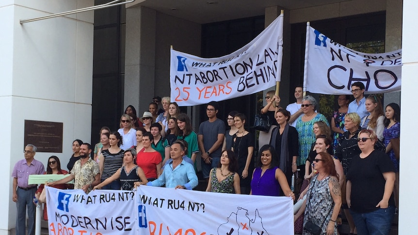 A group of protesters hold banners outside a government building