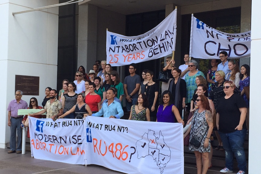 A group of protesters hold banners outside a government building