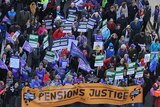 Demonstrators march with flags and placards as they protest during a public service strike over pensions in central Manchester