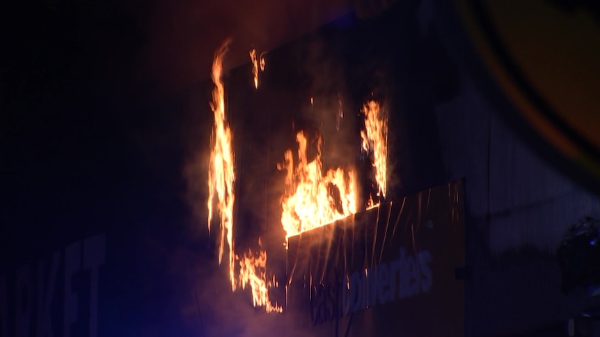 Fire burning through a building at night.