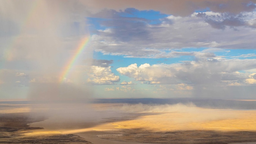 A rainbow shines over Lake Eyre as floodwaters pour in.