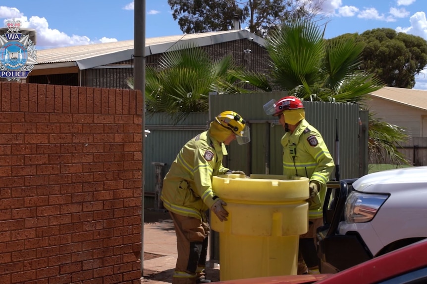 Firefighters transporting dangerous chemicals in a large tub.  
