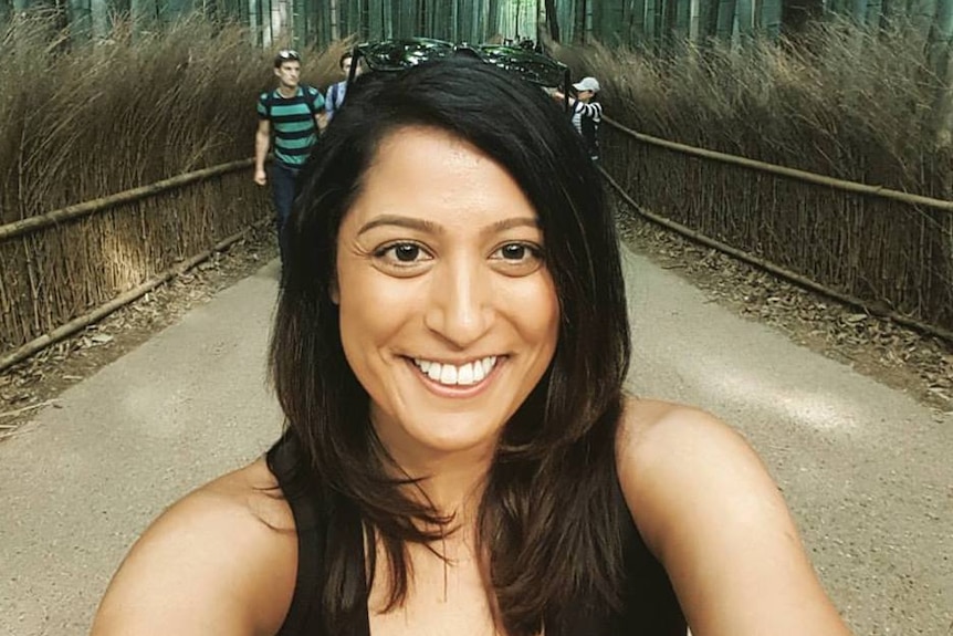 Bhavita Patel smiles at the camera as she walks outdoors.
