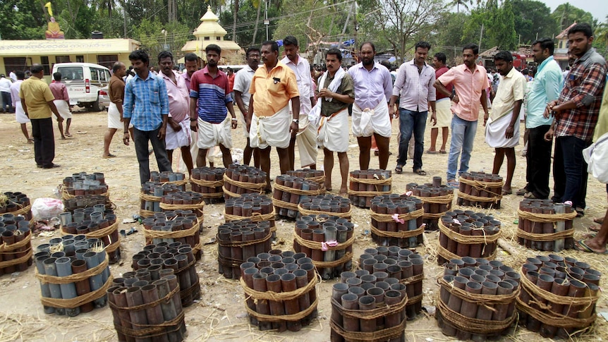 People stand next to empty fire cracker shells inside a temple complex in Kerala, India.