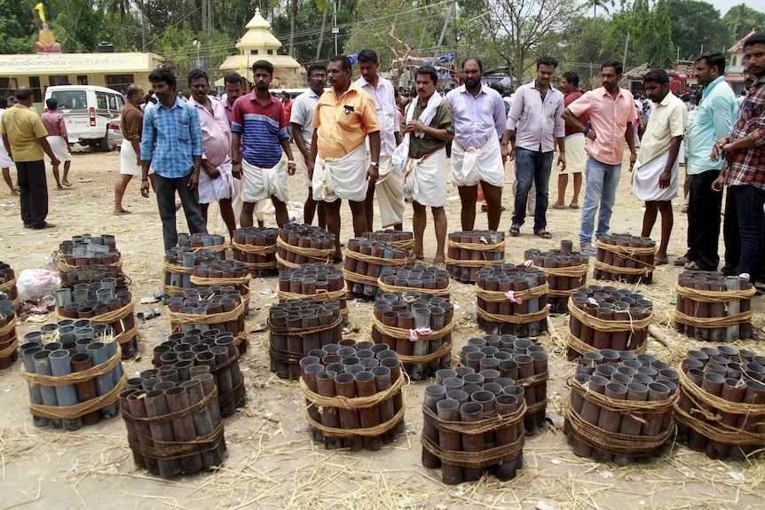 People stand next to empty fire cracker shells inside a temple complex in Kerala, India.