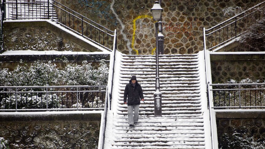 A man walks on snow-covered stairs near the Sacre-Coeur Basilica in the Montmartre district of Paris.