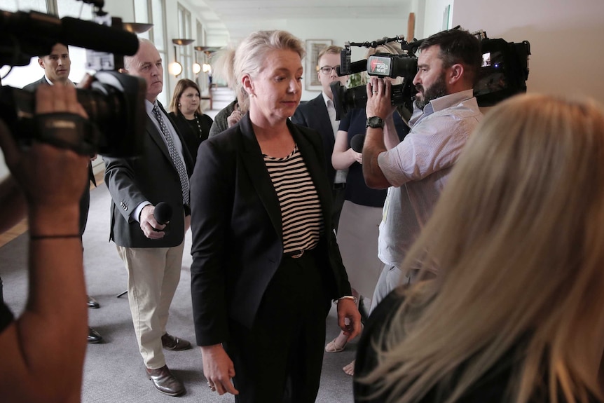 Bridget McKenzie walks away from journalists and cameramen after a press conference inside Parliament House