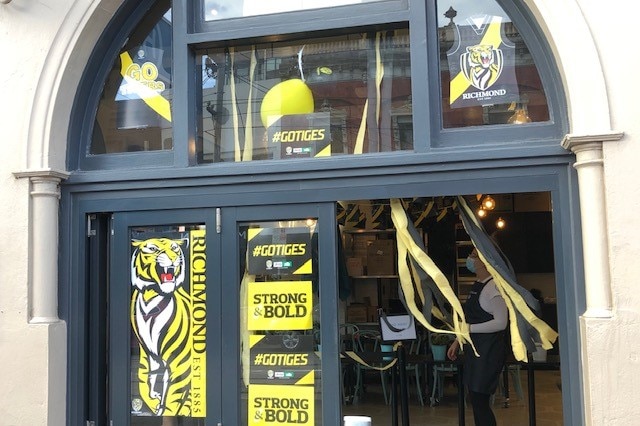 Yellow and black signs reading #GoTiges and Strong and Bold decorate the windows of a Melbourne pub.