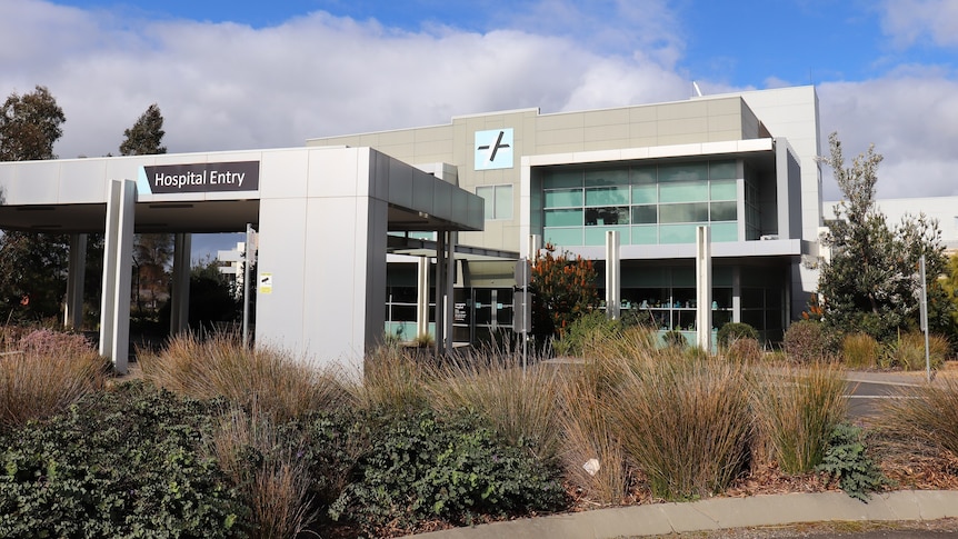 A cream-coloured building surrounded by shrubs.