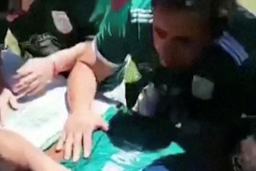 people in green soccer jerseys gather around a coffin laying their hands on top