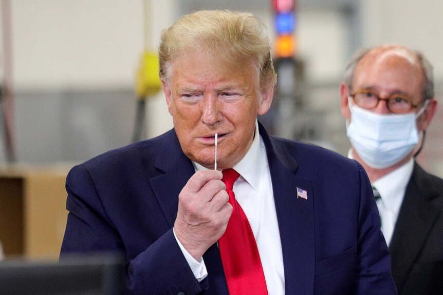 Donald Trump holding a COVID-19 swab to his face