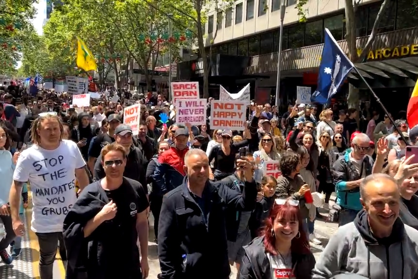 A procession of protesters in a city street holding flags and signs