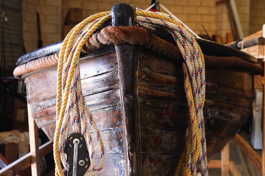 The bow of a historic lifeboat with a coil of rope over the front.