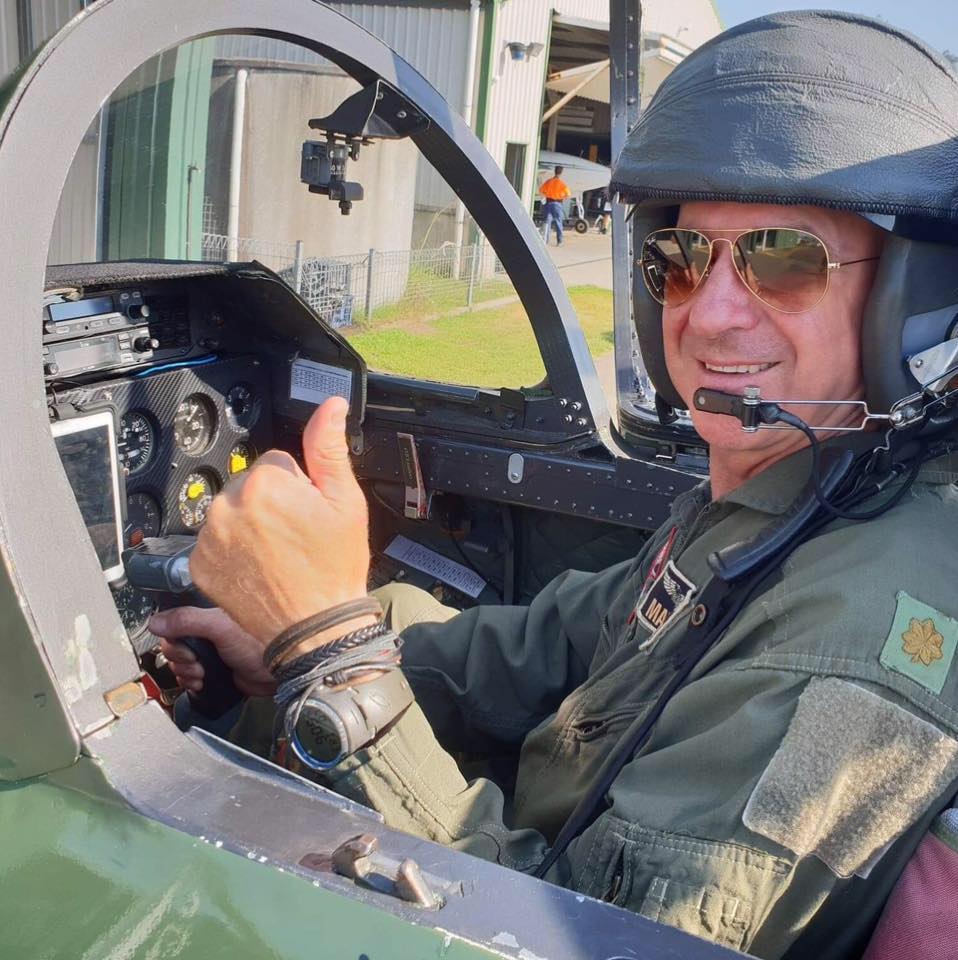 Picture of a man in a helicopter, thumbs up and smiling.