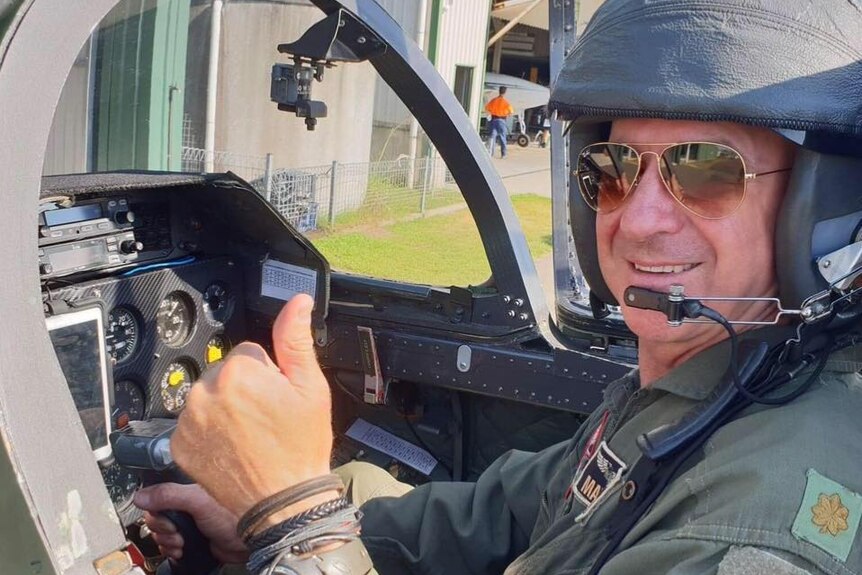 Picture of a man in a helicopter, thumbs up and smiling.