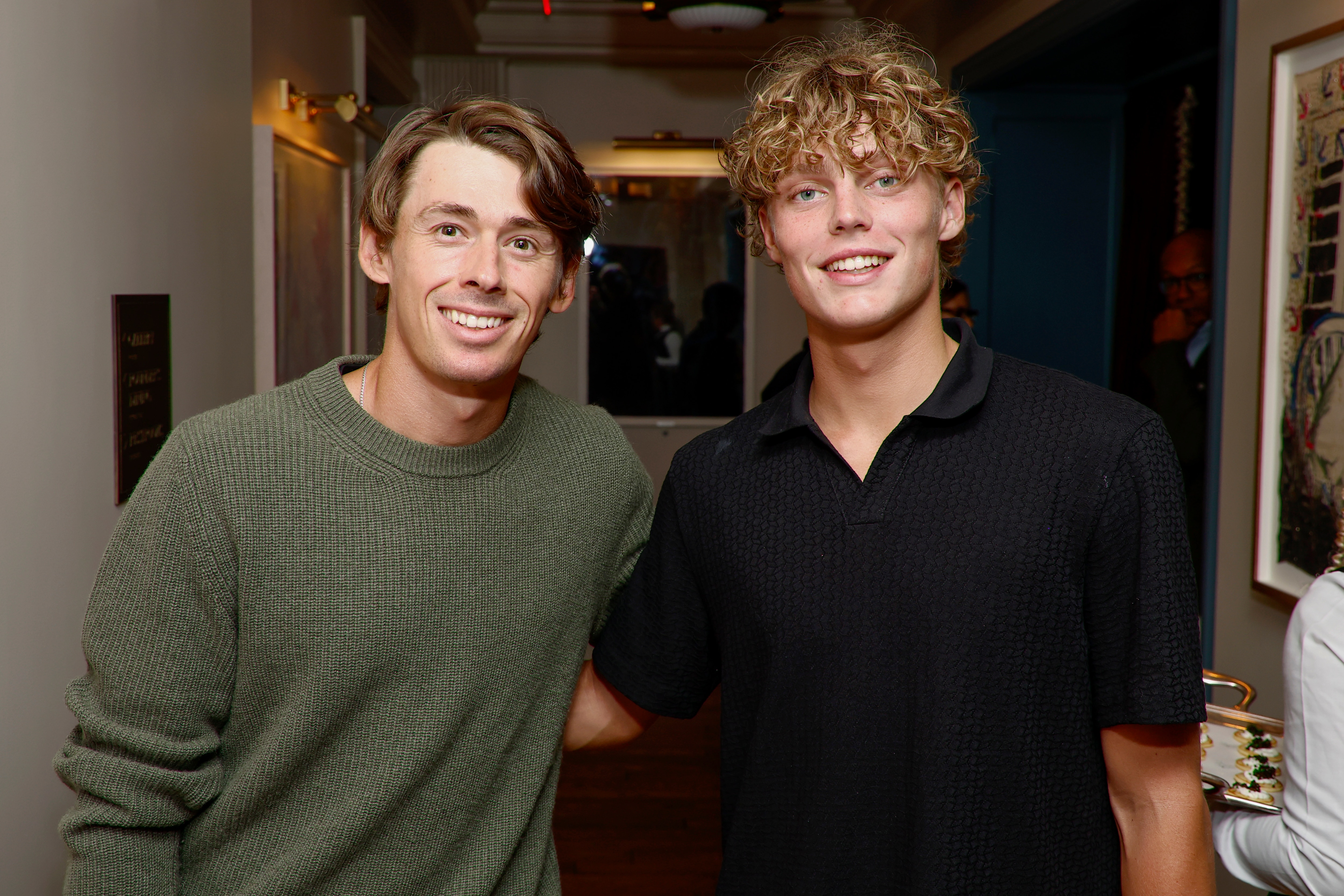 Alex de Minaur and Cruz Hewitt stand next to each other in casual clothing at a pre-tournament function. 