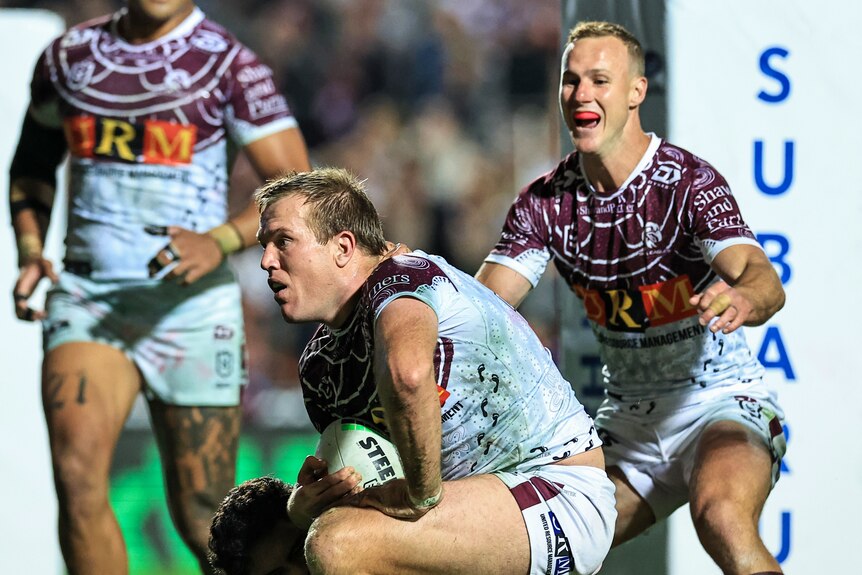 Manly player Jake Trbojevic celebrates scoring, with teammate Daly Cherry-Evans about to hug him from behind
