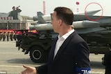 A BBC reporter stands in front of a North Korean missile on a vehicle.