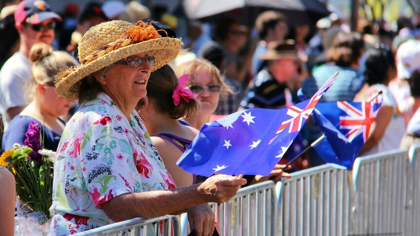 A woman waves an Australian flag as she waits for the royals to arrive