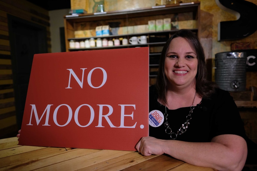 Kim Dowdle holds a sign reading "No Moore".