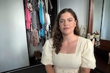 Girl looks at camera in front of clothes cupboard. 