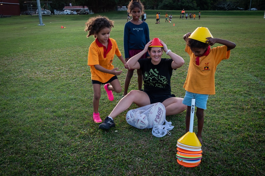 Young women and Aboriginal children playing on football field
