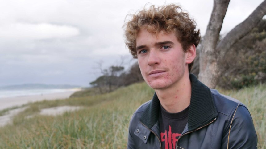 Curtis Cloake sits on the beach in Byron Bay