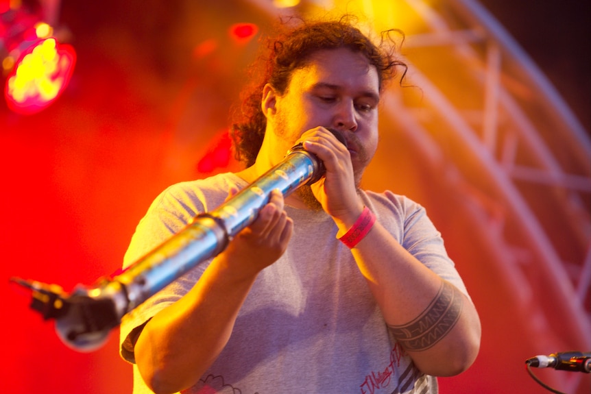 A man on stage playing the didgeridoo 