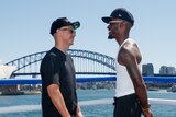 A white man and a black man face off in front of the Sydney Harbour Bridge.