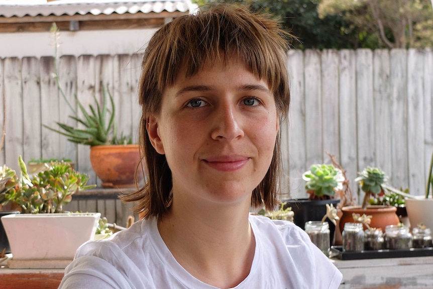 Yoga enthusiast Lauren Anseline sits on outdoor couch, near succulents.