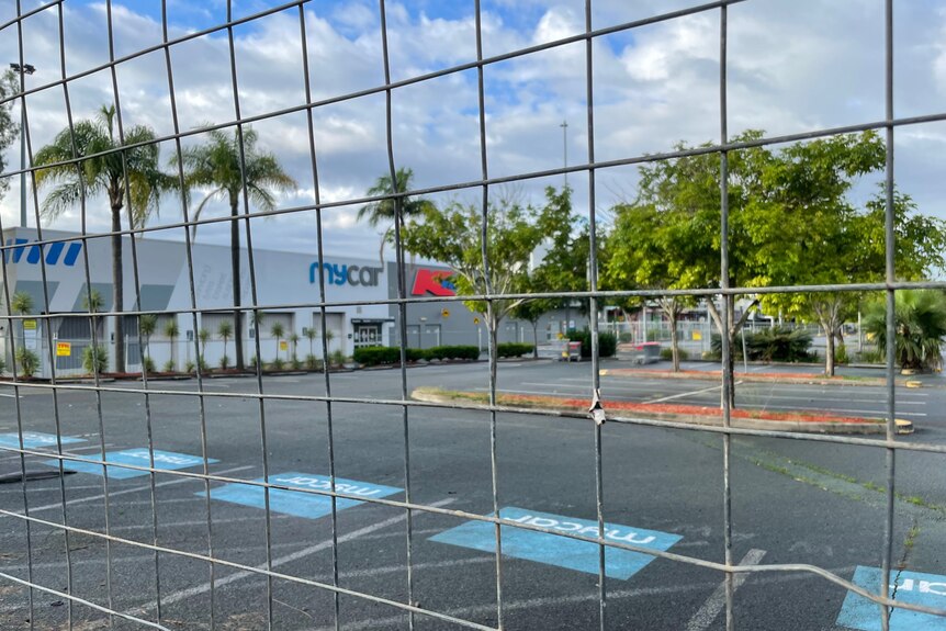 A large car park at a fenced-off shopping centre.