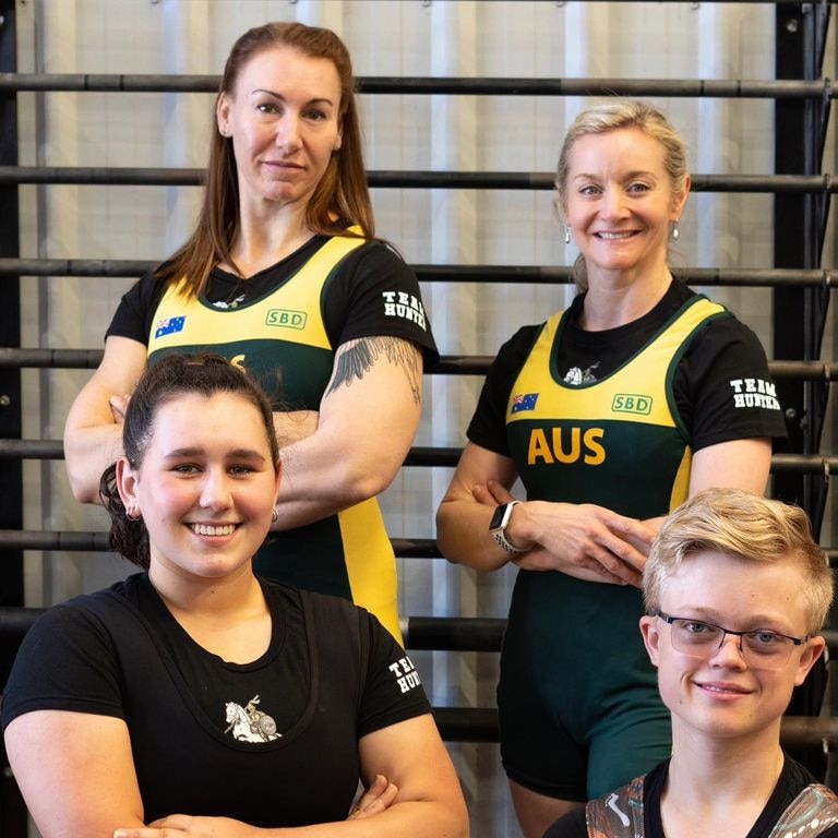 Tres mujeres y Luke vistiendo trajes de levantamiento de pesas de Australia. 