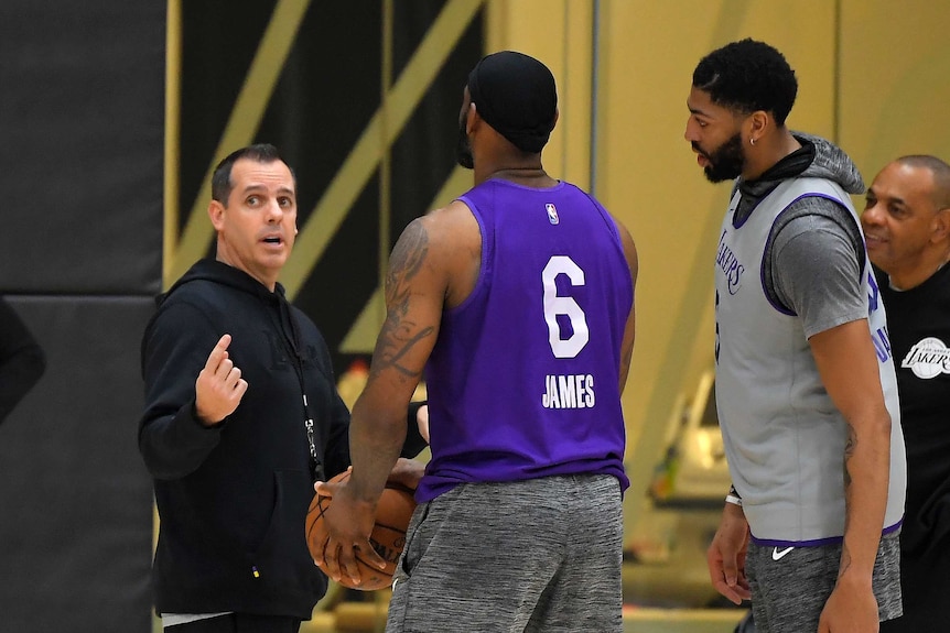Frank Vogel gestures while speaking to LeBron James and Anthony Davis, who are in training gear