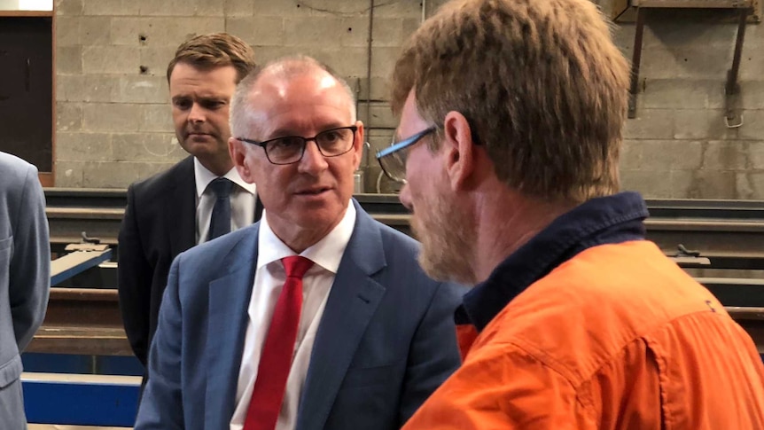 Jay Weatherill talking to someone in an orange high-vis shirt at a media event at QPE Engineering.