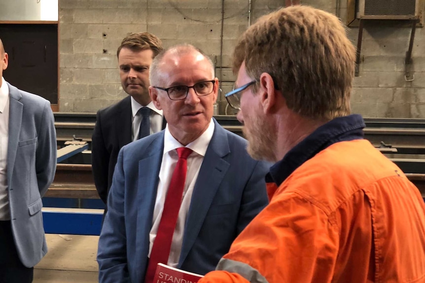 Jay Weatherill talking to someone in an orange high-vis shirt at a media event at QPE Engineering.