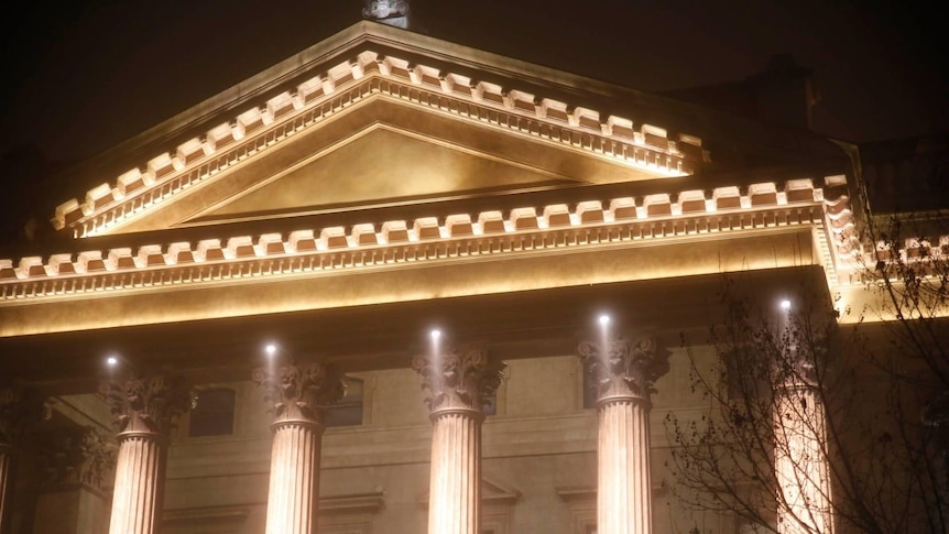 An illuminated theatre facade with its Corinthian columns on a foggy winter's night.