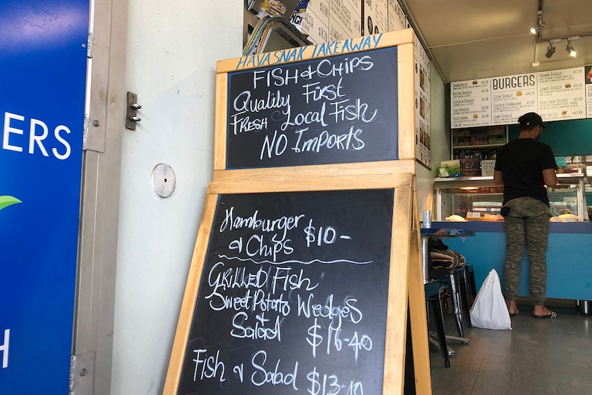 A blackboard in front of a takeaway shop announces 'no imports', only 'fresh local fish' on menu.