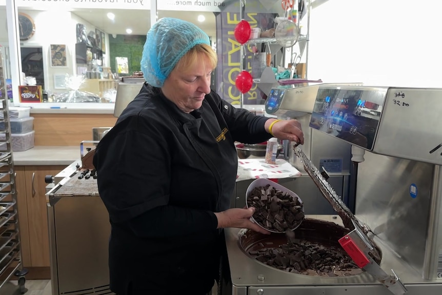 A woman pouring chocolate buds into a machine