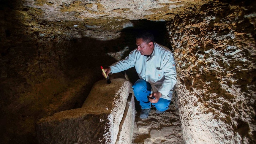 Excavation worker cleaning coffin