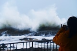 A person standing at a lookout watching huge waves.