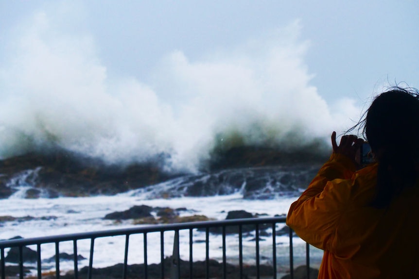 A person standing at a lookout watching huge waves.