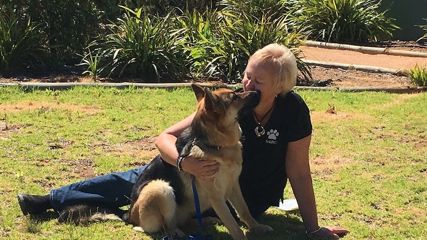 Woman sitting on grass with a dog