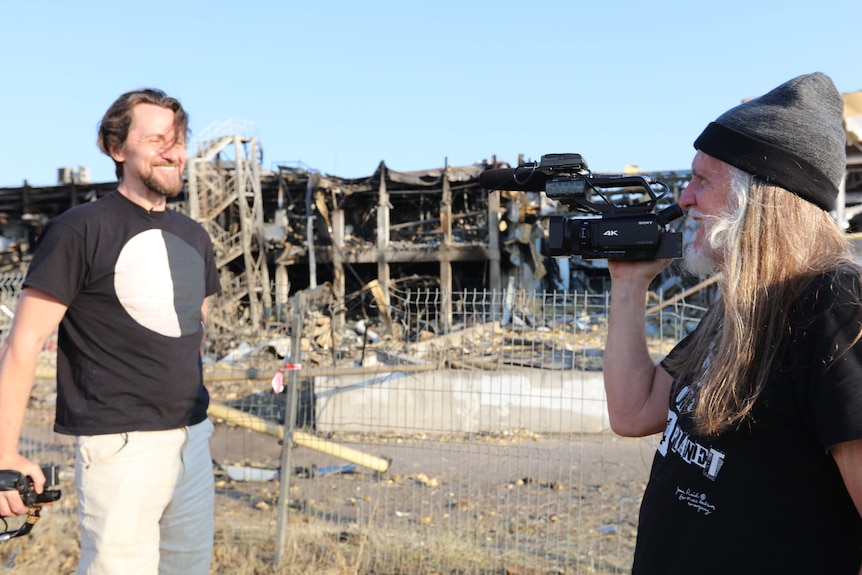 George Gittoes holds a video camera filming a man in Ukraine.