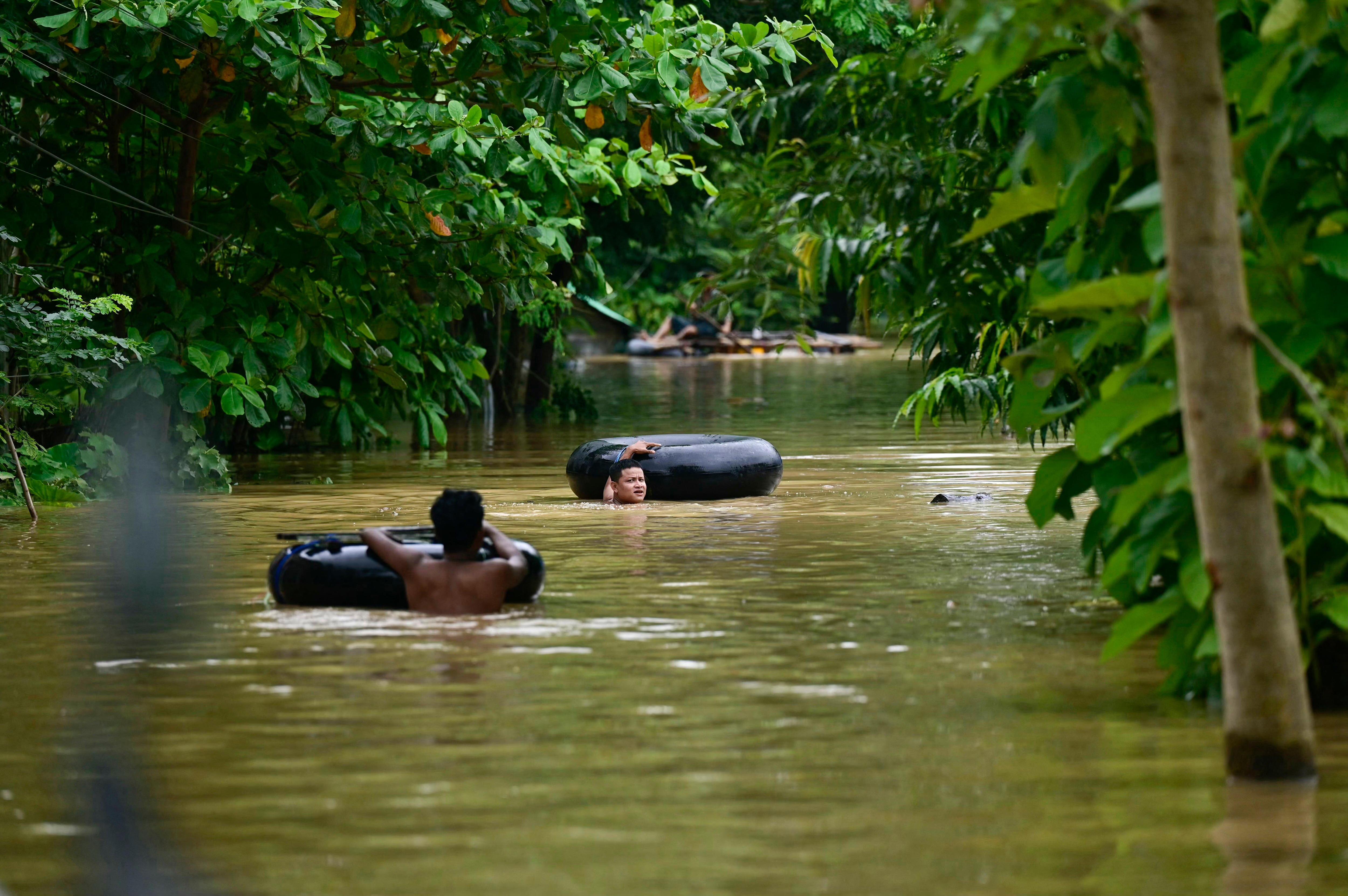 Flood-affected residents use tyre tubes as flotation devices.