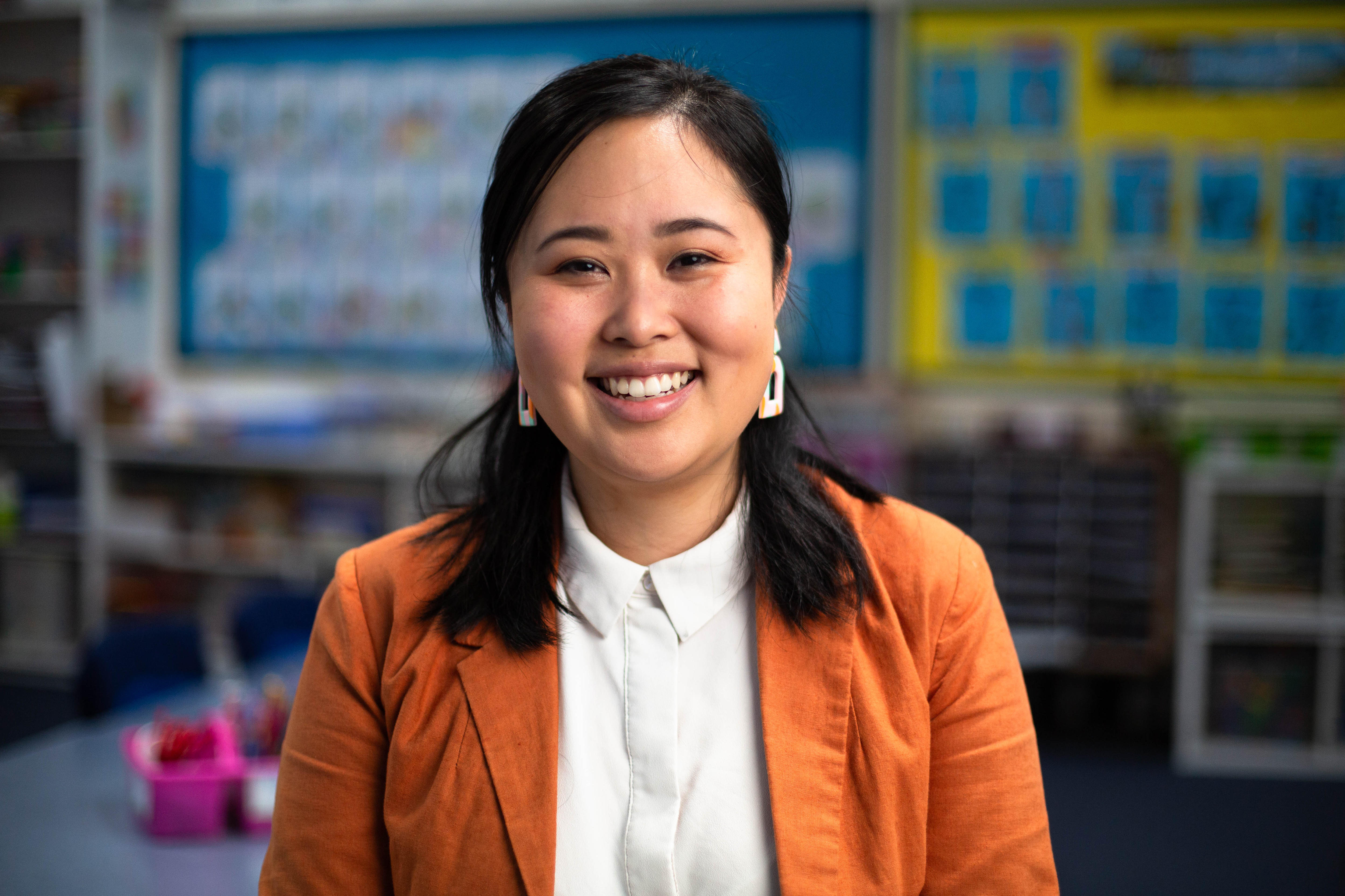 A young Asian woman with black hair smiling in a classroom