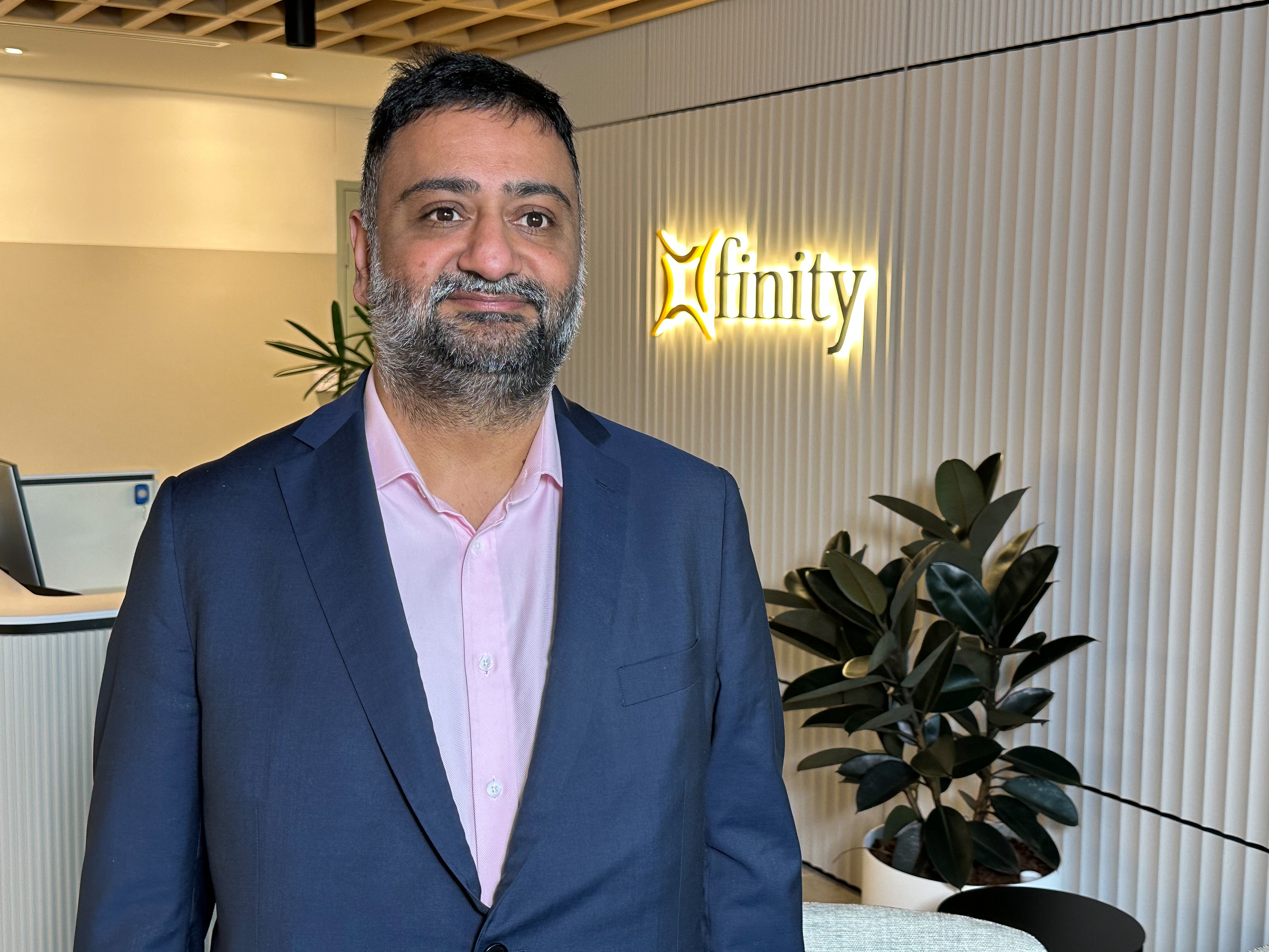 Male professional stands for a photo in front of business signage