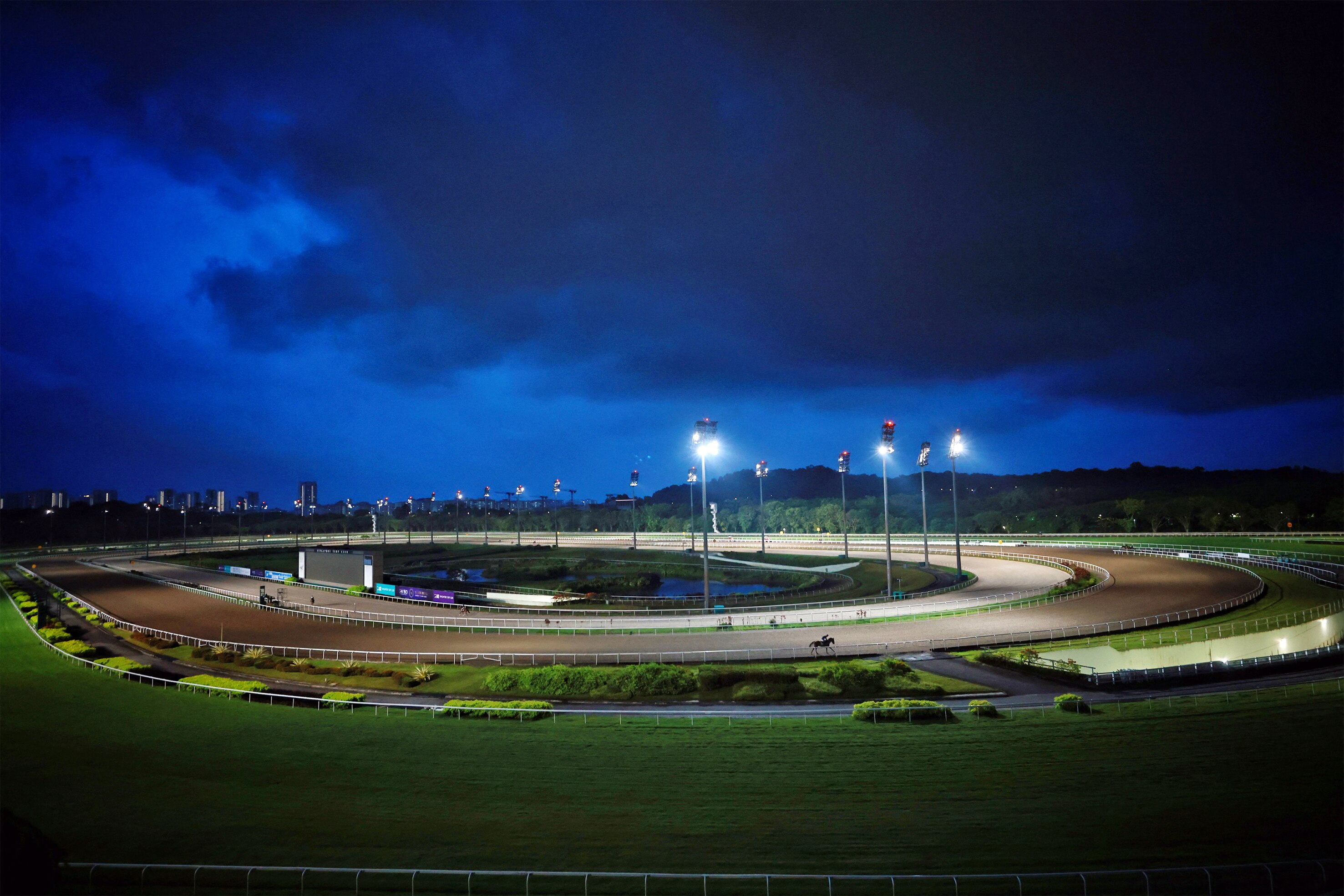 An aerial shot shows a horse racing track light up at night.